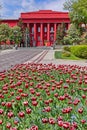 A large red building with columns on the facade against a blue sky with white clouds, in front of the building is a wide Royalty Free Stock Photo