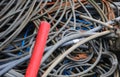 Large red electrical cord and many other tangled used electrical cords in landfill for recycling copper and polluting plastic