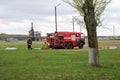 A large red fire rescue vehicle, a truck to extinguish a fire and male firefighters at a chemical, oil refinery against the backgr