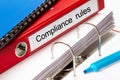 Large red folder for compliance rules including blue ring binder and blue maker Royalty Free Stock Photo