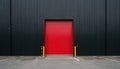 Large red industrial door dominates dark black wall. Stark contrast creates powerful visual statement of strength, minimalism. Royalty Free Stock Photo