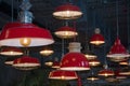 Large red metal chandeliers in the form of pots hang from the ceiling, many lamps.