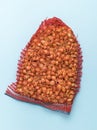 A large red net with onion seeds on a blue background Royalty Free Stock Photo