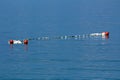 Large red and small white buoys tied with strong rope left floating on surface of calm blue sea