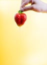 Large red strawberry on bright yellow warm background