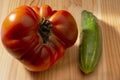 Large red tomato and cucumber on a wooden background Royalty Free Stock Photo