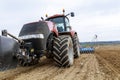 A large red tractor close-up with sowing equipment stands in a field. Royalty Free Stock Photo