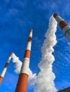 Large red, white brick chimneys of a factory on a blue sky background blowing smoke into the atmosphere on a sunny bright day Royalty Free Stock Photo