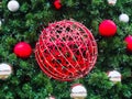 A large red wicker ball entwined with a garland hangs in the center in spruce branches with small red and silver balls