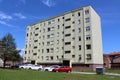 Large renovated apartment building with new windows and light green to yellow facade surrounded with small suburban family houses