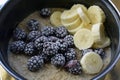 Large, ripe, frozen blackberries and bananas in a pan with oatmeal.