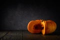 large ripe pumpkin with pulp on a wooden table on a dark gray rough background with a light spot. Thanksgiving Day motives. simple Royalty Free Stock Photo