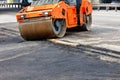 A large road vibratory roller rolls off the highway to lay fresh asphalt on the new road