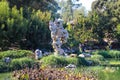 A large rock formation on a deep green lake surrounded by lush green trees in a Japanese garden