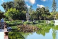 A large rock formation on a deep green lake surrounded by lush green trees in a Japanese garden