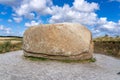 Large rock formation on a gravel road beneath a cloudy blue sky in Nationalpark Thy, Denmark.