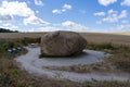 Large rock formation on a gravel road beneath a cloudy blue sky in Nationalpark Thy, Denmark.