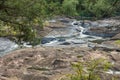 Large rocks making up riverbed with low water level surrounded by green trees Royalty Free Stock Photo