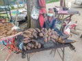 A hill tribe grannie sells barbecued corn cobs and yam roots