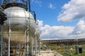 A large round ball-shaped shiny metallic high-pressure iron storage tank for ammonia is strong with pipes and equipment