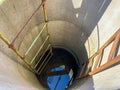 A large round deep well made of concrete rings with clean well underground water for drinking with old rusty stairs Royalty Free Stock Photo