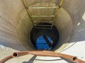 A large round deep well made of concrete rings with clean well underground water for drinking with old rusty stairs Royalty Free Stock Photo
