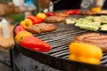 A large round grill on the coals in which grilled color vegetables and fresh meat sausages are cooked. Food and equipment for Royalty Free Stock Photo