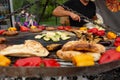 A large round grill on the coals in which grilled color vegetables and fresh meat sausages are cooked. Food and equipment for Royalty Free Stock Photo