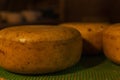 Large round heads of cheese on wooden shelves. Farm production of dairy products. Close-up Royalty Free Stock Photo