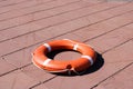 A large round orange plastic life ring for safety and rescue people in the water lies on the stone floor Royalty Free Stock Photo