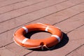 A large round orange plastic life ring for safety and rescue people in the water lies on the stone floor Royalty Free Stock Photo