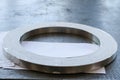 A large round shiny metal ring with small holes, holes, a flange on the working iron table in the factory, the workshop.