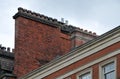 Large row of old fashioned traditional clay chimney pots on a red brick support against a grey sky from when buildings where Royalty Free Stock Photo