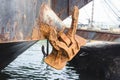 A large, rusted anchored lifted above water while docked at a port