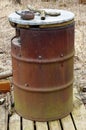 Large rusty barrel is used in the forest as a public ashtray