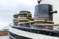 Large rusty bollards with coiled ropes on a ship against a gloomy sky. Mooring in the port. Close-up