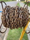 A large rusty chain coiled around a plinth on a street sidewalk