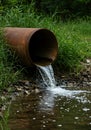 Rusty pipe discharging dirty water into a stream pollution Royalty Free Stock Photo