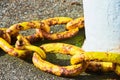 Large rusty old yellow chain on stones. Heavy anchor metal chain in port.