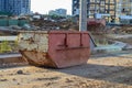 A large, rusty and pink dumpster for construction waste. a container for collecting garbage during the construction of a large