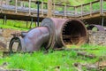 A large rusty steam pipe sitting on a hillside filled with lush green grass and plants surrounded by lush green trees Royalty Free Stock Photo