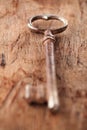 Large rusty vintage metal key on old wooden background