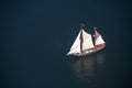 A large sailboat goes to sea under sail. View from above.