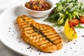 The large salmon steak red fish on the grill with lemon, sauce and greens