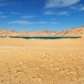 Large sandy bright dunes of the desert with an oasis under the hot rays of the scorching sun