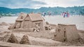 a large sand castle on a beach with a house in the middle