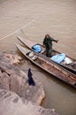 Large Sand stone canyon cliff shoreline of Mekong river and local Thai fisherman working in wooden boat