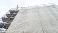 Large scaffolding on a building with an empty gray tarpaulin