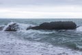 Large sea waves cover huge stone boulders