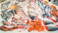 A large selection of fresh fish lying in the ice on the counter of the supermarket.